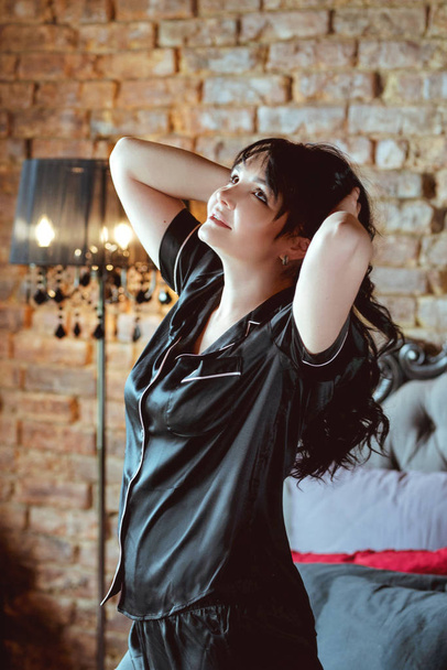 όμορφη μελαχρινή γυναίκα με μαύρο μετάξι πυτζάμες στο κρεβάτι - Φωτογραφία, εικόνα