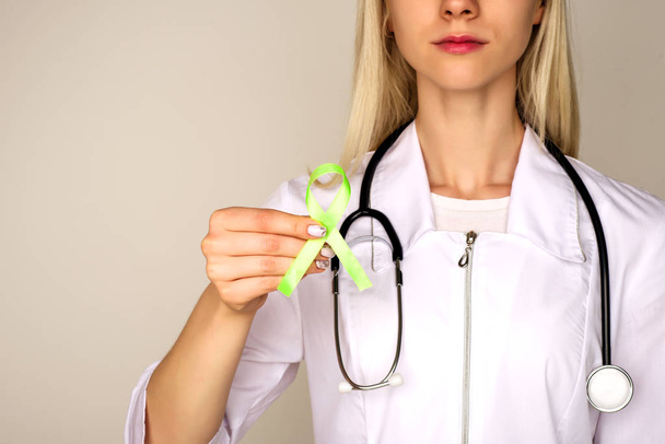Vrouwelijke arts in wit uniform met licht groen lint Awareness - Foto, afbeelding