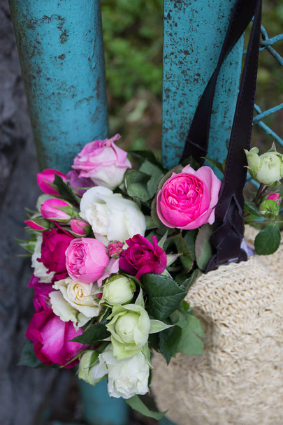 bouquet of fragrant English pink and white roses in a bag of raffia hanging on the fence - Valokuva, kuva