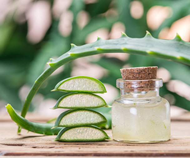 Fresh aloe leaves and aloe gel in the cosmetic jar on wooden tab - Photo, Image