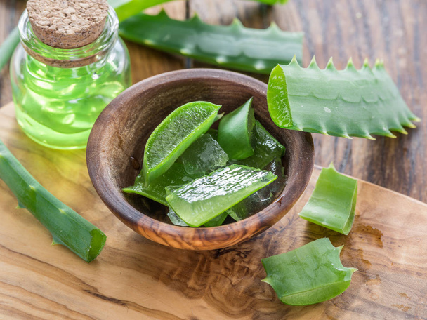 Fresh aloe leaves and aloe gel in the cosmetic jar on wooden tab - Photo, image