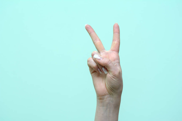 женские пальцы показывают знак победы на изолированном фоне. Концепция - успешное завершение дела
 - Фото, изображение