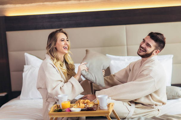 ευτυχισμένο ζευγάρι που έχοντας μαξιλάρι καταπολέμηση σε δωμάτιο ξενοδοχείου  - Φωτογραφία, εικόνα