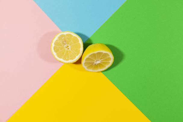 Un limón de corte amarillo se extiende sobre una superficie plana de colores verde, azul, rosa y amarillo
 - Foto, Imagen