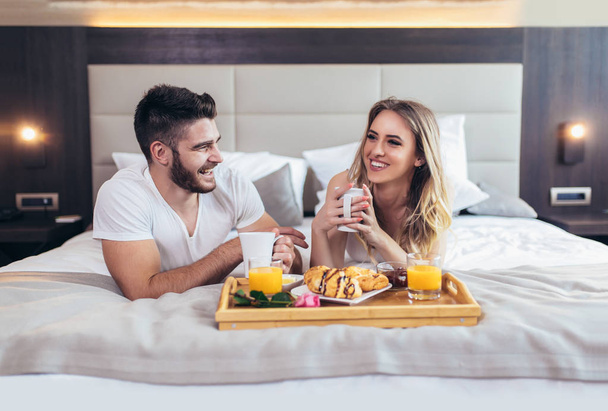 Romantic happy couple having breakfast in bed - Фото, зображення