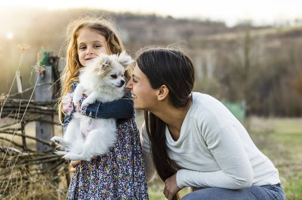 Happy countryside family with their cute white pomeranian dog - Zdjęcie, obraz