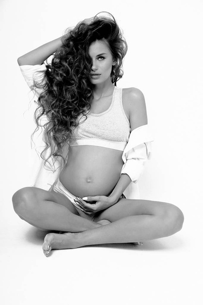 schöne schwangere Frau mit dunklem lockigem Haar in Dessous und - Foto, Bild