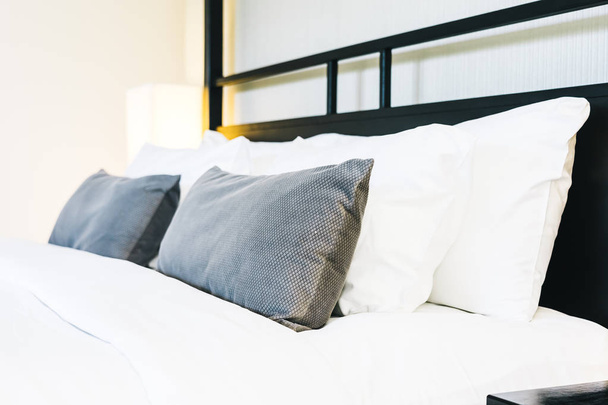Mooie luxe comfortabele kussen op bed met licht lamp - Foto, afbeelding
