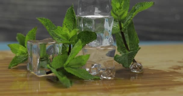 Cubos de hielo y hojas de menta aisladas en tabla de cortar de madera
 - Metraje, vídeo