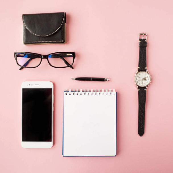 Stationery, white smartphone, glasses, pen, wallet, watch, calendar, notebook. Pink background. - Fotografie, Obrázek