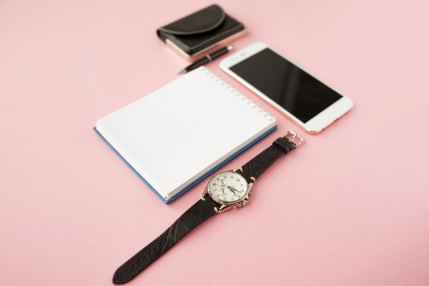 Stationery, white smartphone, pen, wallet, watch, calendar, notebook. Pink background. - Fotografie, Obrázek