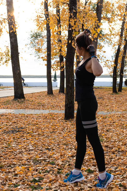 Χαμπάροφσκ, Ρωσία-07 Οκτ, 2018: νέα αθλητική γυναίκα που τεντώνει και ετοιμάζεται να τρέξει. Ελκυστική γυναίκα σε αθλητικά ρούχα κάνει αθλητικές ασκήσεις στη φύση, στο χαλί των φύλλων του φθινοπώρου, αγαπά γυμνάστρια - Φωτογραφία, εικόνα