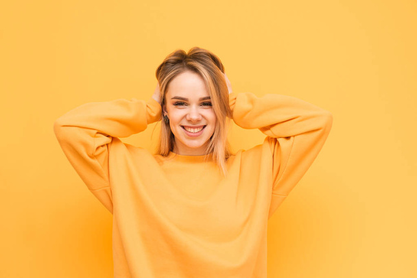 Happy model porte des vêtements orange, pose sur un fond jaune, regarde dans la caméra et sourit. Portrait lumineux d'une adolescente sur fond jaune, riant et posant. Isolé
 - Photo, image