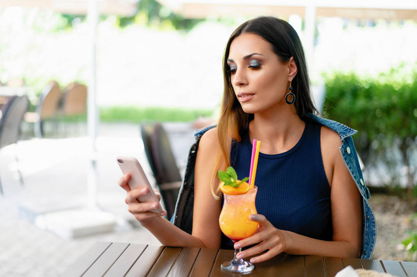 A beautiful smiling woman is drinking an exotic cocktail in an o - Fotoğraf, Görsel