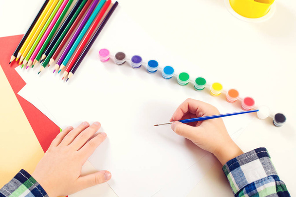 Le mani del bambino sono dipinte con vernici colorate e pennello su una carta
.  - Foto, immagini