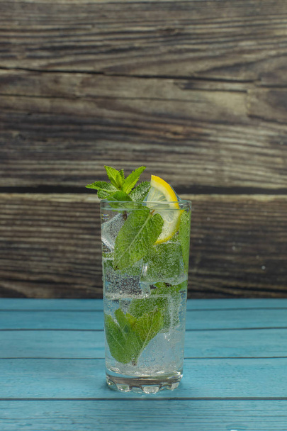 Чистая вода в стакане с зелеными листьями мяты и кубиками льда
 - Фото, изображение