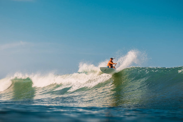 12 kwietnia 2019. Bali, Indonezja. Stand Up Paddle surfer jeździć na fali oceanu. Stand Up wiosło surfowanie po falach na Bali - Zdjęcie, obraz