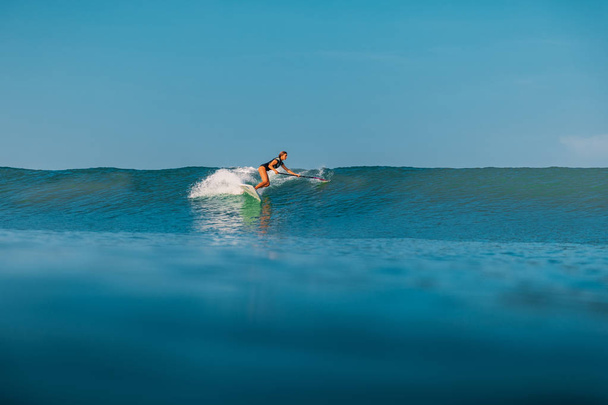 2019年4月12日インドネシア、バリ島。海の波に乗ってパドルサーファーを立ち上がる。バリ島の波でパドルサーフィンを立ち上がる - 写真・画像