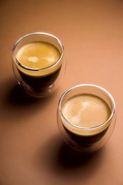 Café negro con espuma en copas modernas sobre un fondo liso
 - Foto, imagen