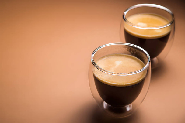 Черный кофе с пеной в современных чашках на обычном фоне
 - Фото, изображение