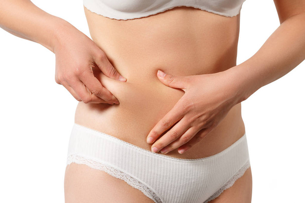 woman in white underwear takes extra fat on the sides of her stomach with her hand. isolate on white background - Photo, Image