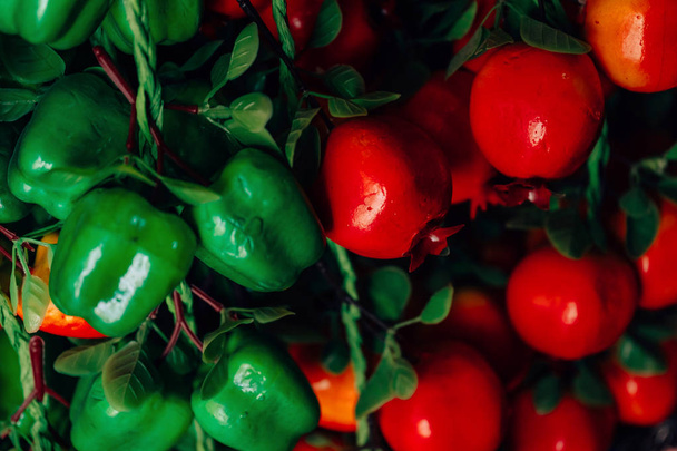 gefälschtes Obst und Gemüse. Dekorative künstliche Beeren und Früchte im Inneren. grüne Paprika und Tomaten. - Foto, Bild