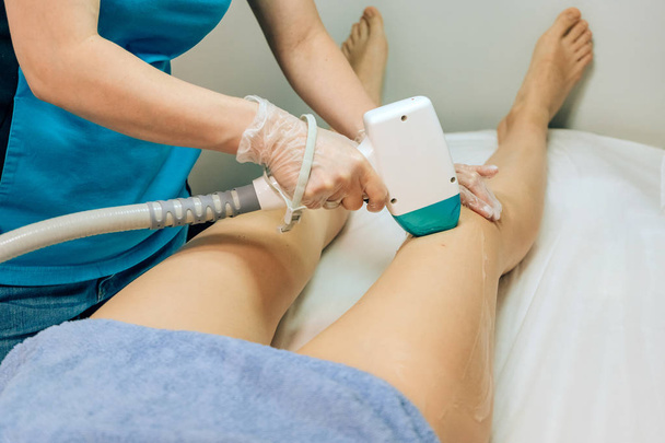 Laser hair removal girls. Hair removal on the legs of a woman. Destruction of the hair follicles with a laser. A radical method of hair removal. The use of laser radiation in the office beautician - Foto, Imagem