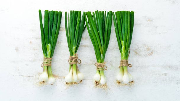 Green onion on a white wooden background. Top view. Free space for text. - Zdjęcie, obraz