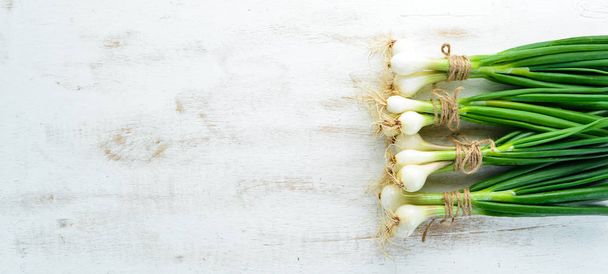 Green onion on a white wooden background. Top view. Free space for text. - Φωτογραφία, εικόνα