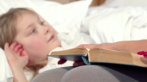 Loving mother reading fairytale to her daughter before sleep - Footage, Video