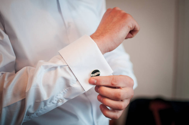 Um noivo que fixa um botão de punho antes de se casar
 - Foto, Imagem