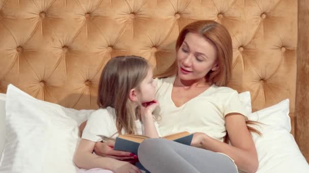 Attractive woman enjoying reading a book with her adorable little daughter - Footage, Video
