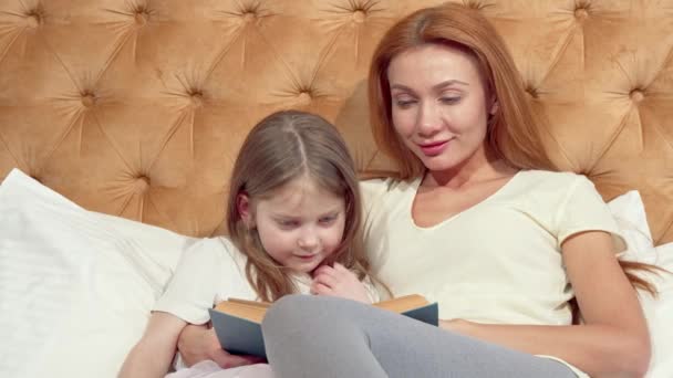 Krásná Holčička a její krásná matka se usmívají na kameru a čtou si knížku - Záběry, video