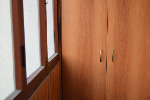 Застекленная лоджия с деревянным шкафом на балконе, система хранения и концепция безопасности и страхования собственности и частной собственности
 - Фото, изображение