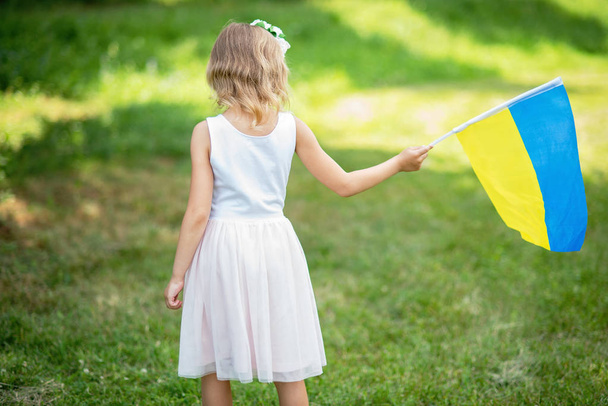 little girl carrying fluttering blue and yellow flag of Ukraine in field, Ukraine Independence Day concept - Φωτογραφία, εικόνα