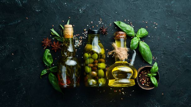 Olive oil, olives and spices on a black stone background. Top view. Free space for your text. - Foto, Imagem