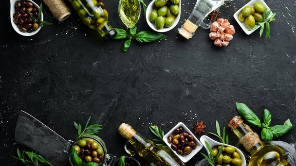 Olive oil, olives and spices on a black stone background. Top view. Free space for your text. - Zdjęcie, obraz