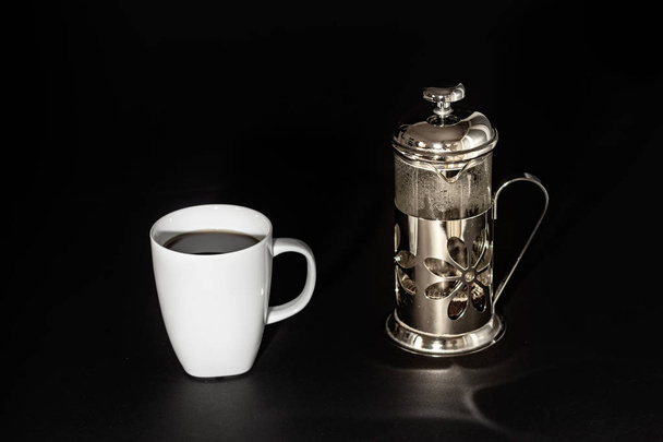 A cup - mug of coffee with a plunger - french press coffee maker over black background. - Foto, Imagem
