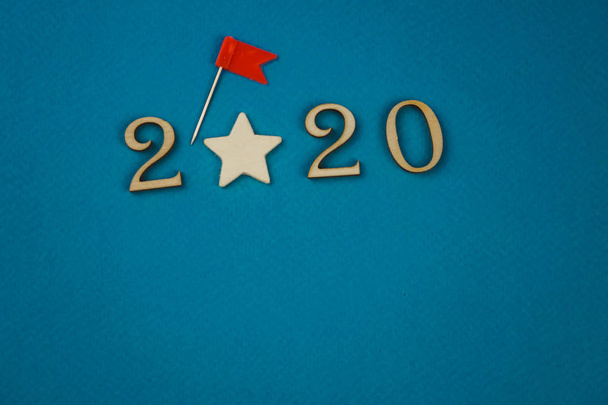 2020 numero puusta numerot sinisellä pohjalla hajallaan tähdet vaihteet ja liput ympäri
 - Valokuva, kuva
