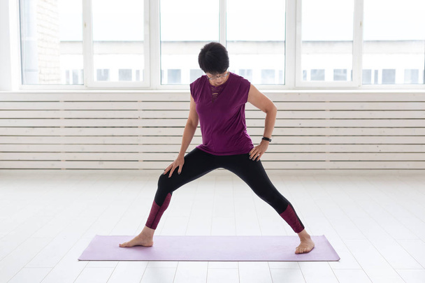 Healthy lifestyle, people and sport concept - Middle aged woman doing yoga - Photo, Image