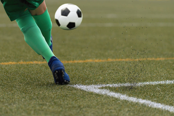 Voet van een kind football-speler en de bal op het voetbalveld - Foto, afbeelding