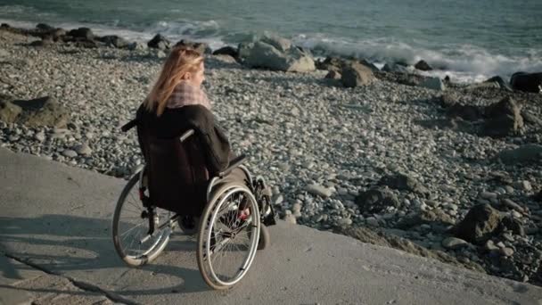 Mulher com deficiência está sentado em transporte inválido e olhando para o mar
 - Filmagem, Vídeo