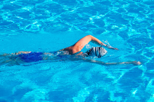 γυναίκα με μαγιό που κολυμπάει σε μια γαλάζια πισίνα. - Φωτογραφία, εικόνα