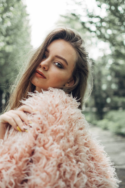Portré egy stílusos lány rózsaszín kabát pózol az utcán - Fotó, kép