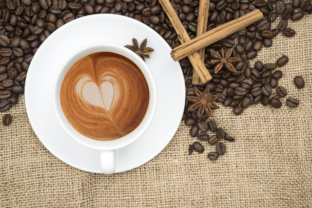 Cup of coffee with heart shape in foam on hessian background - 写真・画像