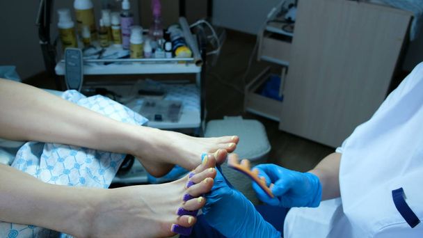 steril eldiven çivi ustası ayak ayırıcıları çıkarır - Fotoğraf, Görsel