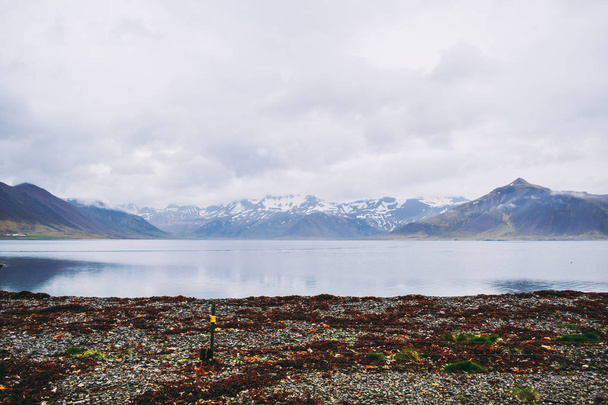 Beaux sommets enneigés des montagnes islandaises de l'autre côté du lac. Belle ligne de côte et reflet du ciel et des sommets de montagne dans l'eau
. - Photo, image