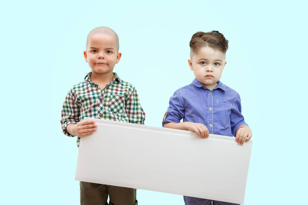 Portrait de deux garçons tenant une pancarte blanche sur fond isolé - Photo, image