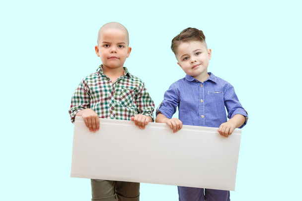 孤立した背景に白い看板を持つ2人の少年の肖像 - 写真・画像