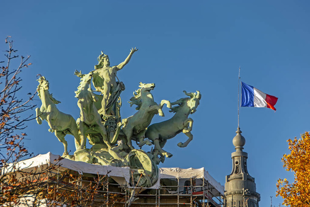 Hermosos monumentos famosos Estatua de Quadriga y bandera francesa contra el cielo azul en París, Francia. Cielo azul y caballos de bronce verde saltando desde el techo del palacio. L 'Inmortalite devancant le Temps
 - Foto, imagen